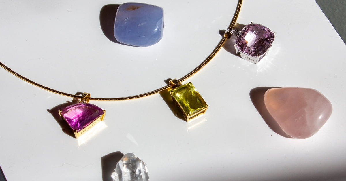 Macro close-up of a model holding the diamond-encrusted bail between her fingertips. Cast in 18K yellow gold, this shot highlights the precise setting of the emerald-cut yellow quartz pendant paired with the fine, fluid links of the gourmette chain.