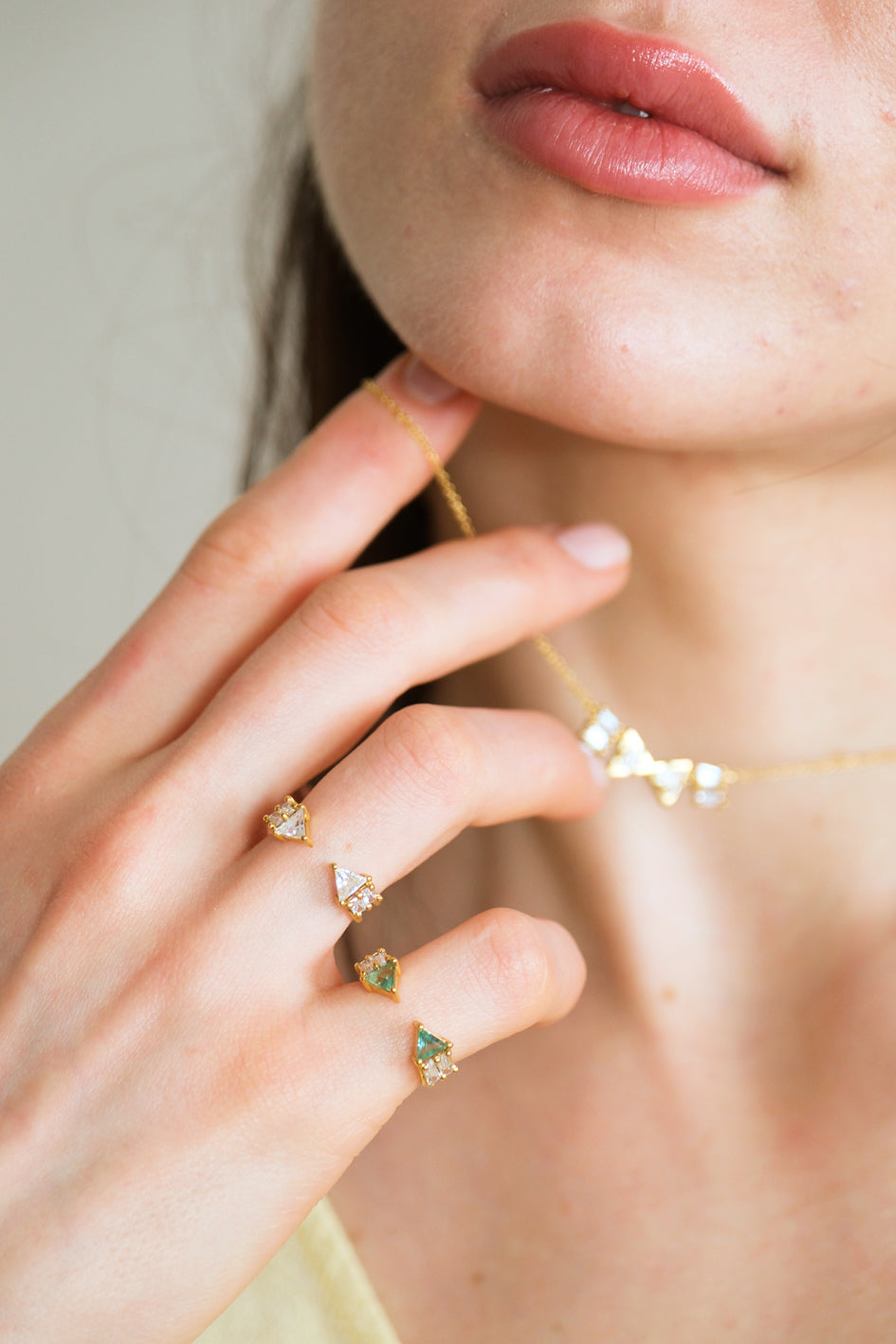 Model wearing Atlante Emerald and Diamond rings with the Atlante Diamond necklace H in the blurry background