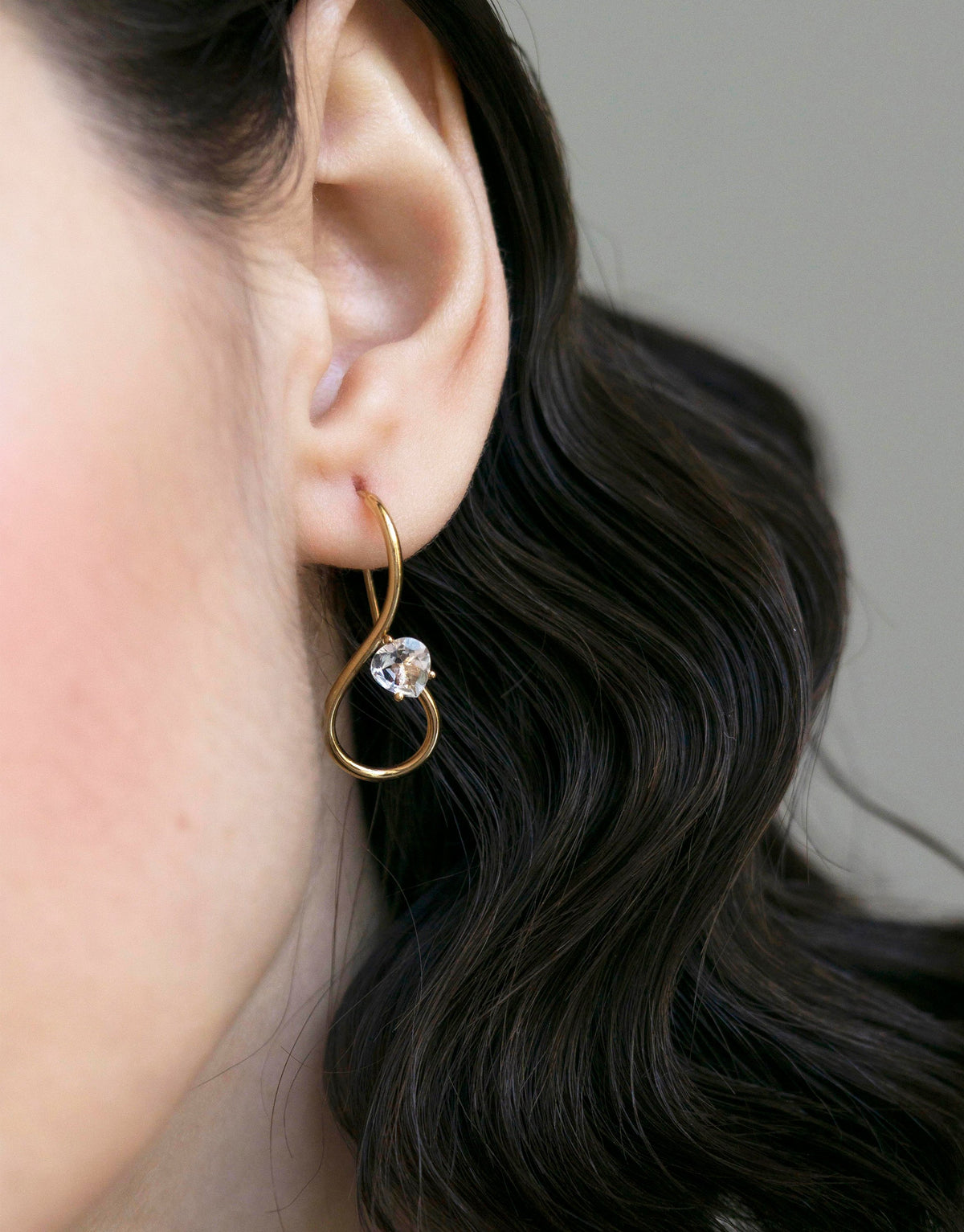 Infinity Earrings in 9k yellow gold with a round cut white topaz by Nayestones, Belgian fine jewelry.