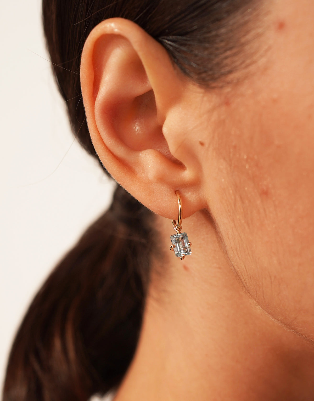 Bloom petite creole earring in 9K yellow gold with an octagon-cut blue topaz by Nayestones, Belgian Fine Jewelry.
