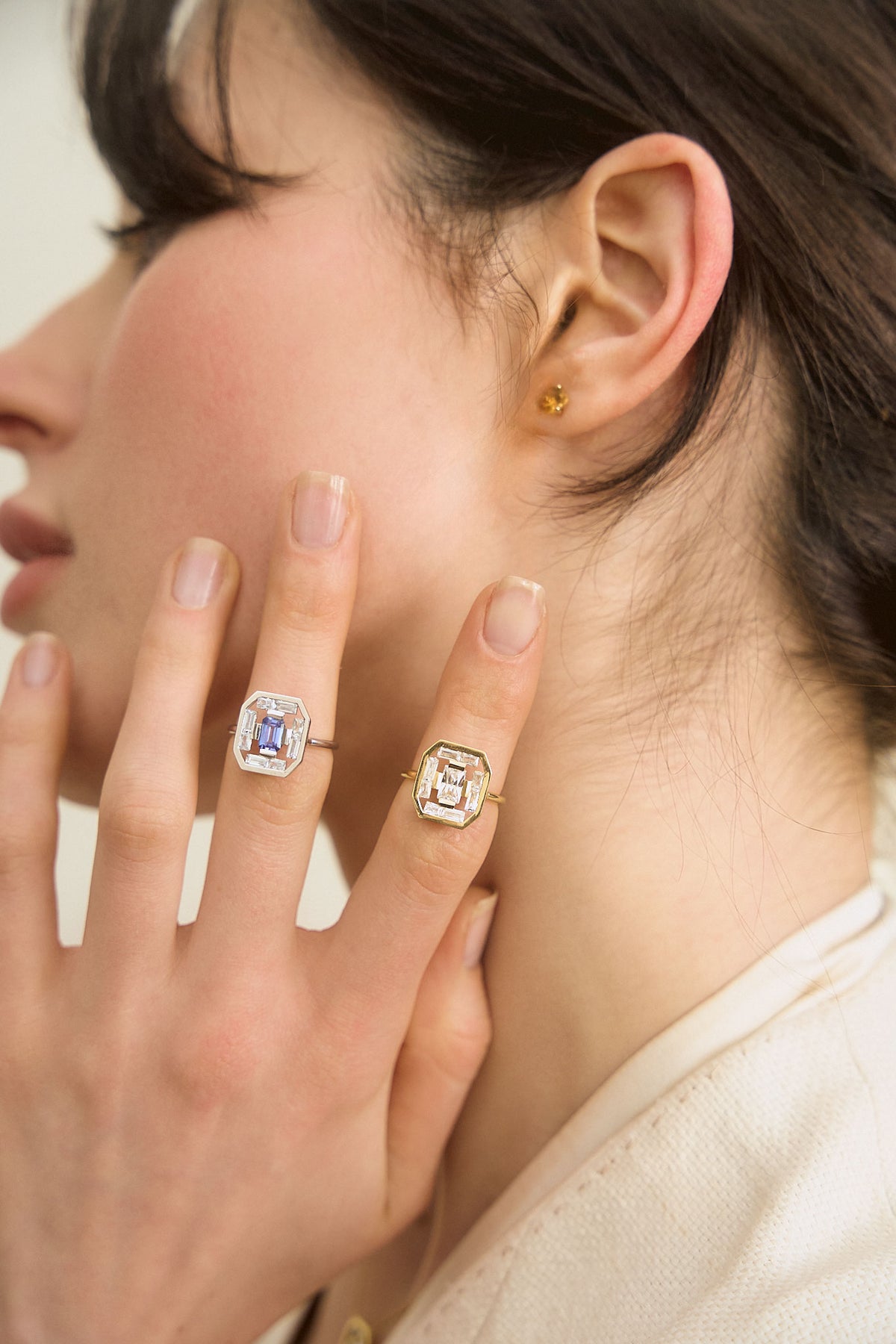 Woman's hand wearing two rings in 18-carat white and yellow gold. Rings from the Art Deco collection, with an octagonal stone in the center, surrounded by a row of baguette-cut diamonds. 