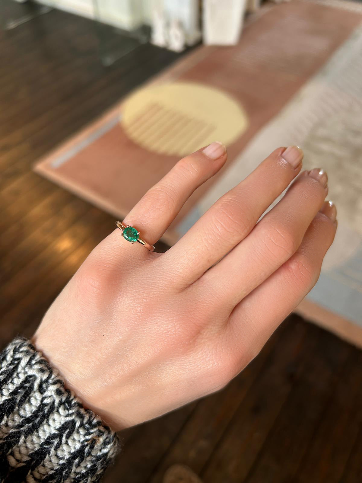 Woman's hand wearing the Gaia Emerald ring by Nayestones on her pinky finger, in 18K pink gold featuring a central oval-shaped emerald.
