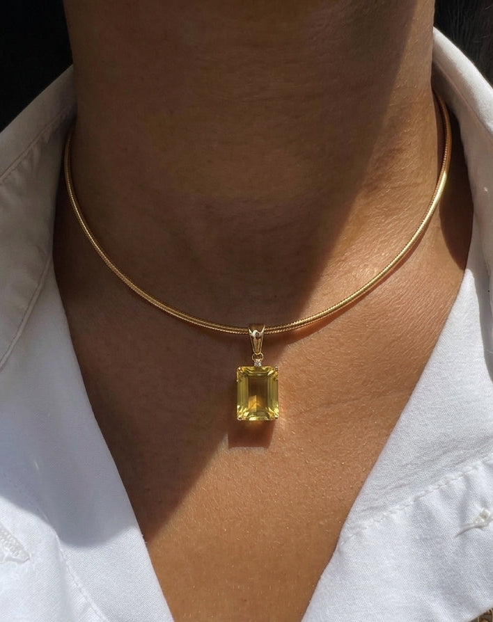 The model is wearing our yellow gold OMEGA CHAIN with our GEMORA PENDANT from the GEMORA COLLECTION.