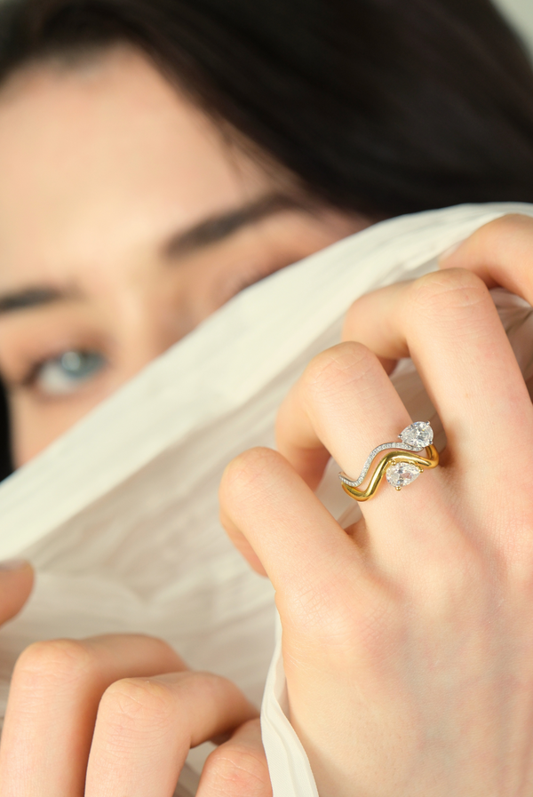 Model's hand with 2 rings from the Petite Comète collection on her ring finger, one in 18K white gold paved with diamonds, and the other in 18K yellow gold with thicker metal. Both rings are set with a 0.7-carat pear-shaped diamond. Nayestones