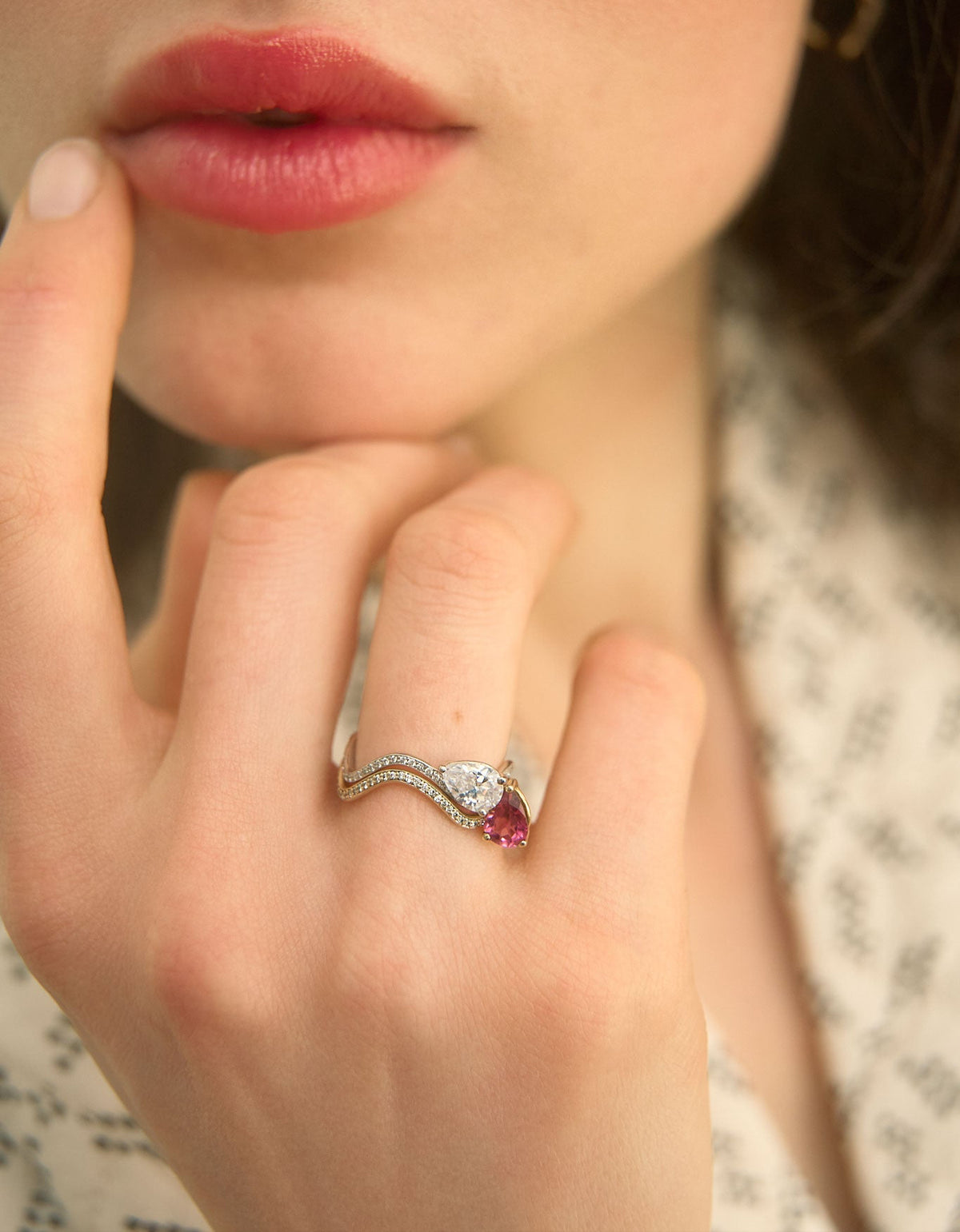 Model's hand wearing two Petite Comète engagement rings in 18K white gold ring with a 0.7-carat Pear Star Diamond and a Pear Pink Tourmaline, both paved with diamonds, by Nayestones, Belgian fine jewelry.