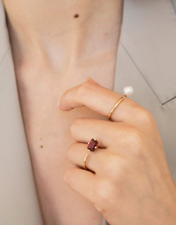 Model wearing two Signature Octogone engagement ring in 9k yellow gold with an octagon-cut rhodolite and one with a round pearl by Nayestones, Belgian Fine Jewelry. Nayestones