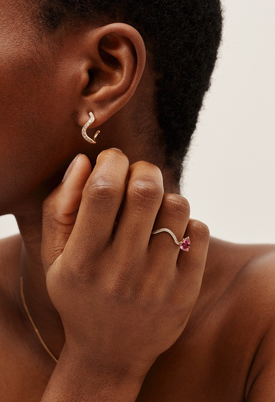 petite comete earring pave setting diamond on ear in 18k gold with petite comete engagement ring in yellow gold with a pear cut pink tourmaline. by Nayestone, Belgian fine jewelry. 