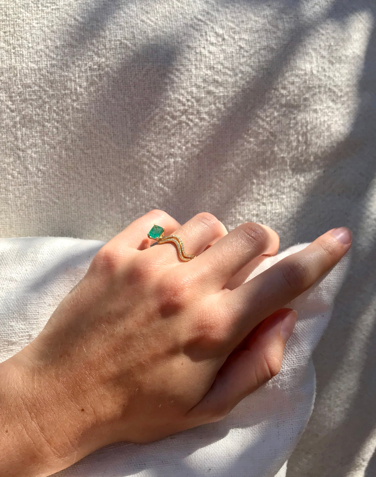 Petite comete wedding and engagement ring in 18k yellow gold and a baguette cut emerald and double pavé diamonds by Nayestones, Belgian creative jewelry. 